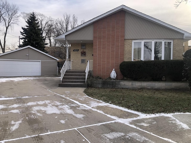 view of front of house featuring a garage, brick siding, and an outdoor structure