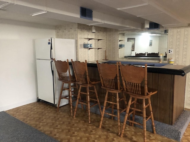 bar featuring visible vents, bar area, and freestanding refrigerator