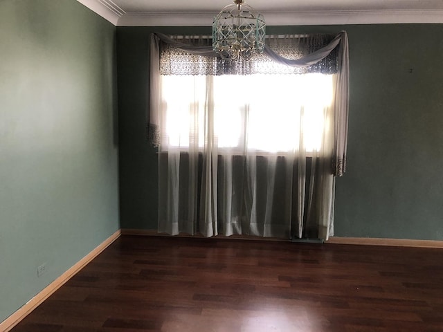 spare room with a chandelier, ornamental molding, wood finished floors, and baseboards