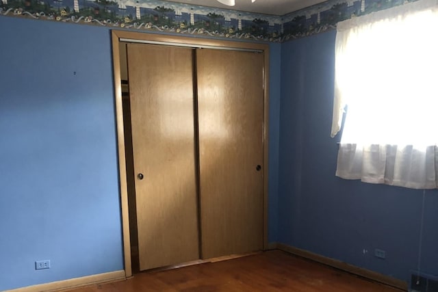 unfurnished bedroom with baseboards, visible vents, a closet, and wood finished floors