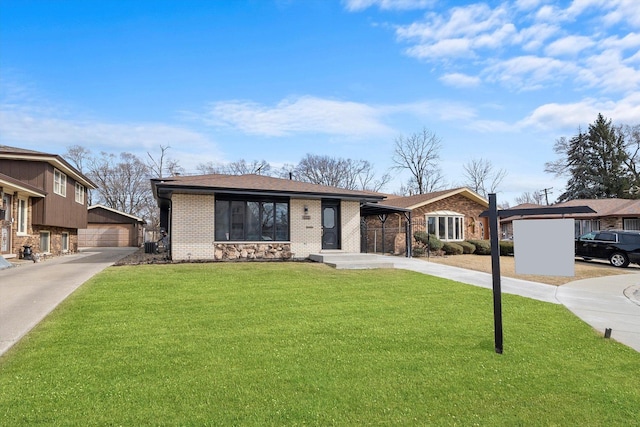 view of front of house featuring brick siding, an outdoor structure, a detached garage, and a front lawn