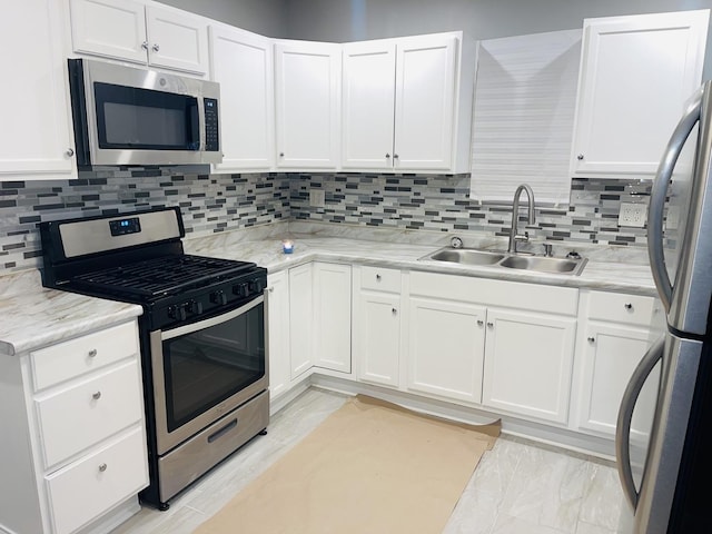 kitchen featuring stainless steel appliances, a sink, white cabinets, and decorative backsplash