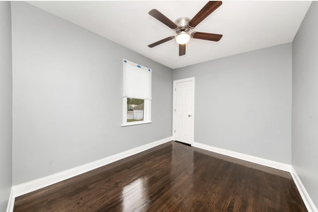 empty room with wood finished floors, a ceiling fan, and baseboards