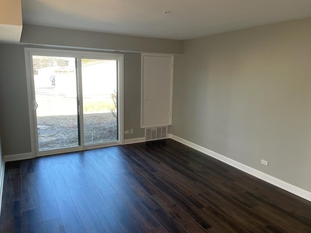 unfurnished room featuring dark wood-style flooring, visible vents, and baseboards