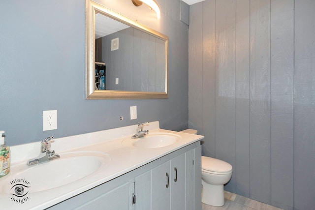 full bathroom featuring toilet, double vanity, and a sink