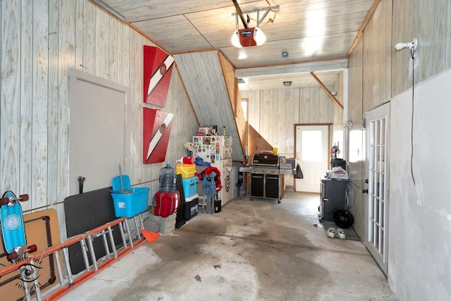 interior space featuring a garage door opener, freestanding refrigerator, and wood walls