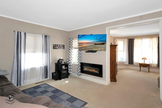 living area with carpet, a glass covered fireplace, and crown molding