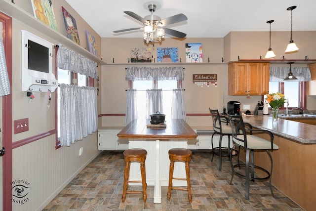 kitchen featuring a peninsula, stone finish flooring, a kitchen bar, and a sink