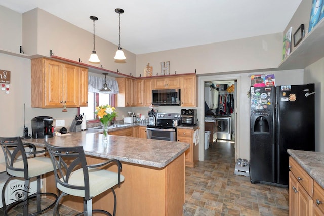 kitchen with washer / dryer, a peninsula, stone finish flooring, stainless steel appliances, and light countertops