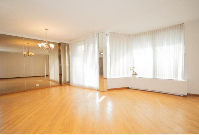 empty room with a notable chandelier and wood finished floors