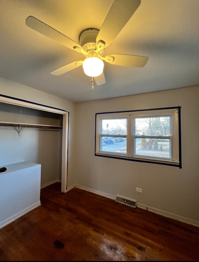 unfurnished bedroom with visible vents, multiple windows, baseboards, and dark wood-style flooring