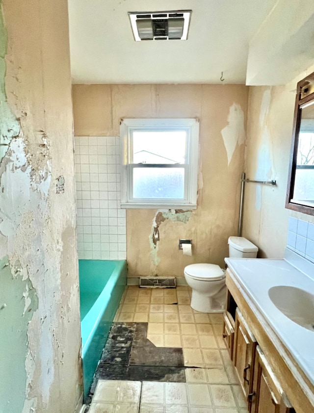 full bathroom featuring tile patterned floors, visible vents, toilet, a tub, and vanity