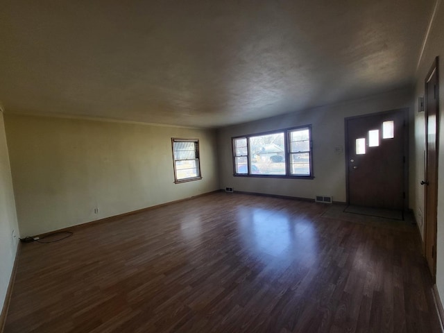 interior space with dark wood-type flooring, visible vents, and baseboards