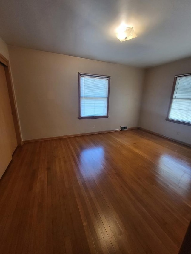 unfurnished room featuring baseboards, visible vents, and hardwood / wood-style floors