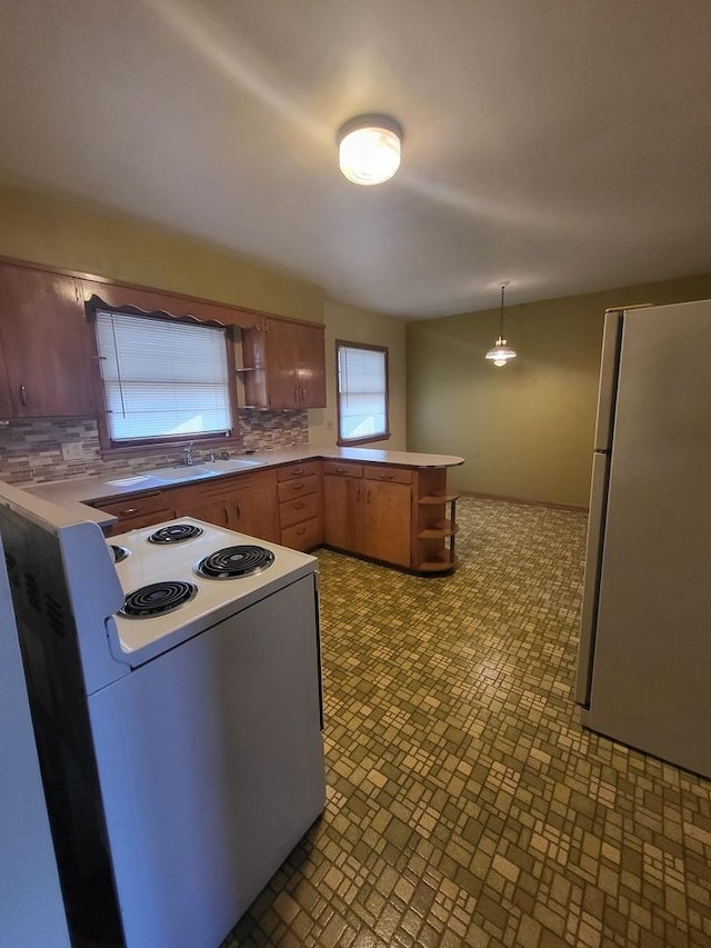 kitchen with white appliances, tasteful backsplash, a peninsula, open shelves, and a sink