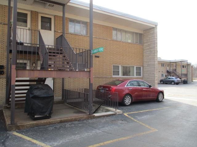 view of property featuring uncovered parking and stairway