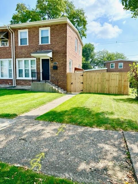 view of front of property with a gate, a front yard, fence, and brick siding