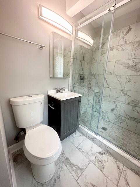 full bathroom featuring toilet, marble finish floor, a shower stall, and vanity