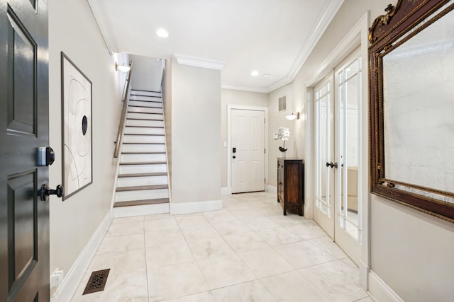 foyer with crown molding, light tile patterned floors, visible vents, baseboards, and stairs