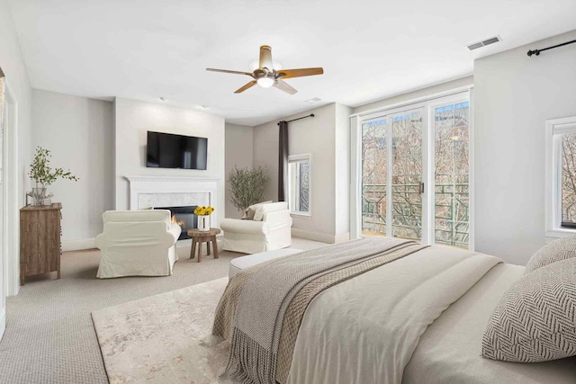 carpeted bedroom featuring ceiling fan, a high end fireplace, visible vents, and baseboards