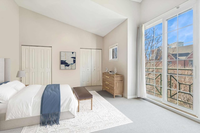 bedroom featuring baseboards, vaulted ceiling, two closets, and carpet flooring