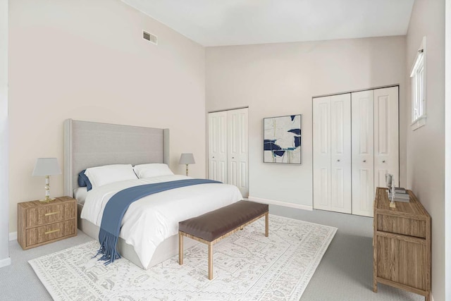 carpeted bedroom with baseboards, visible vents, and multiple closets