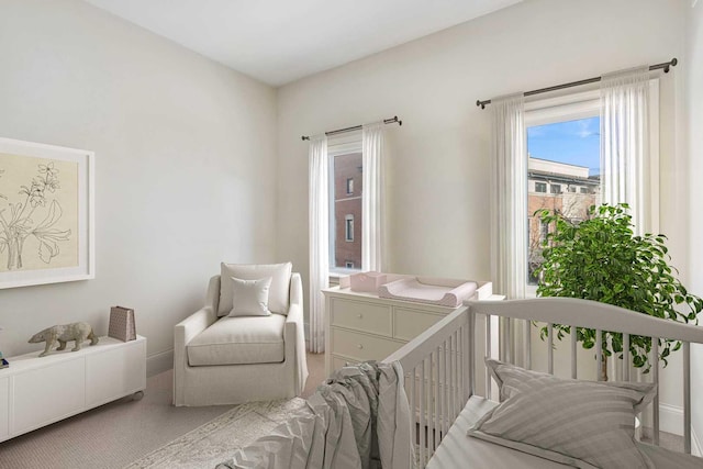 carpeted bedroom featuring a nursery area