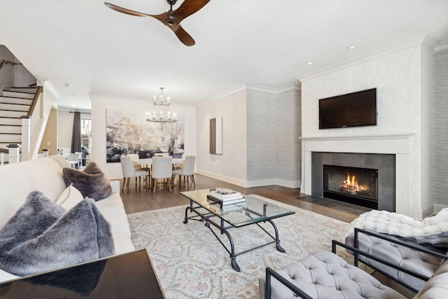 living room featuring wallpapered walls, stairway, ornamental molding, wood finished floors, and a fireplace