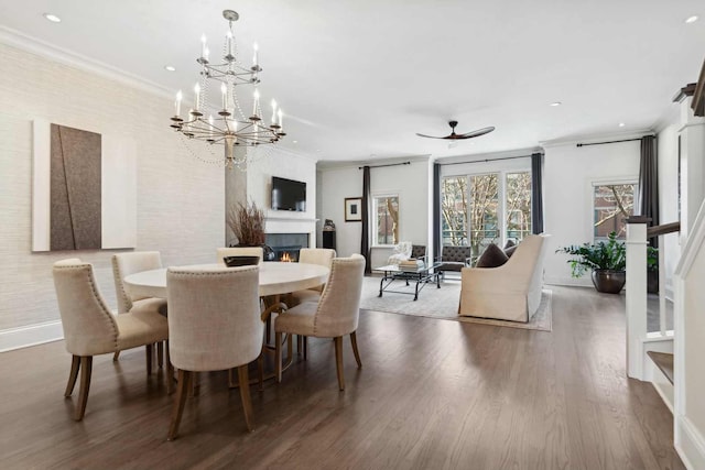 dining space with crown molding, recessed lighting, wood finished floors, a warm lit fireplace, and baseboards