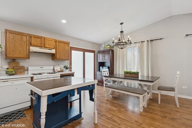 kitchen with lofted ceiling, light countertops, a chandelier, white appliances, and under cabinet range hood