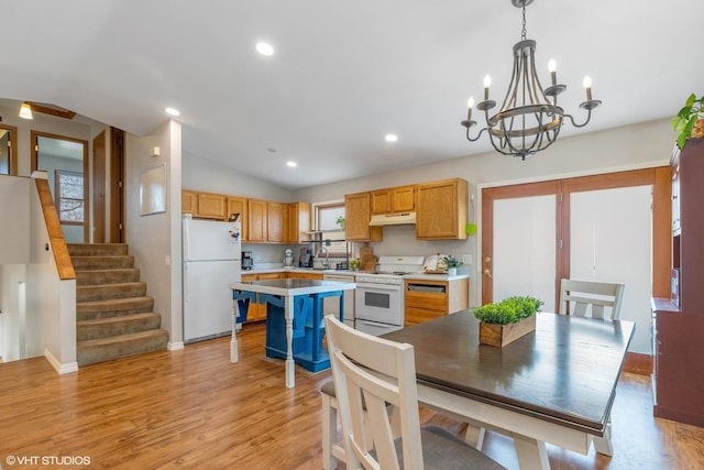 kitchen with lofted ceiling, under cabinet range hood, white appliances, light countertops, and light wood-type flooring