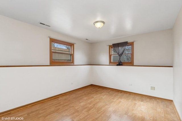 empty room with light wood-type flooring, baseboards, and visible vents