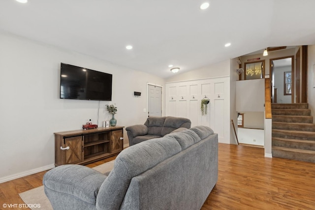 living room featuring light wood finished floors, baseboards, lofted ceiling, stairs, and recessed lighting