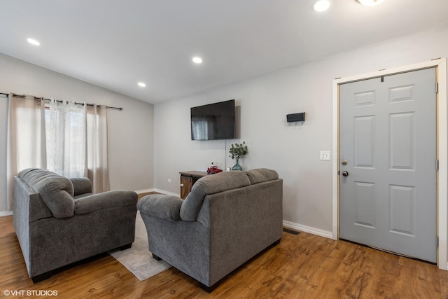 living area featuring visible vents, baseboards, wood finished floors, vaulted ceiling, and recessed lighting