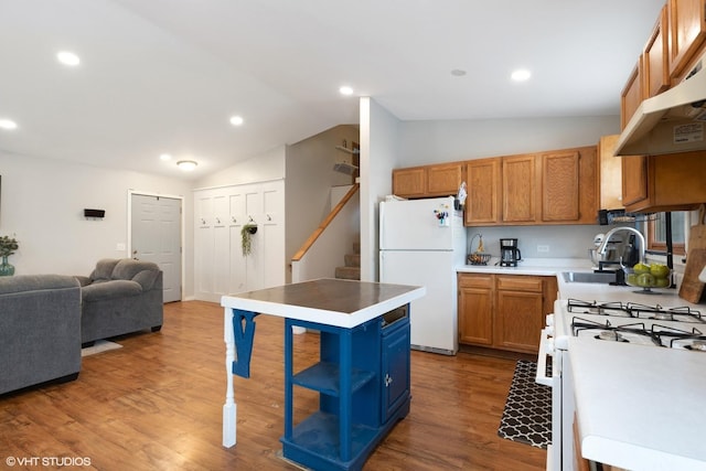 kitchen with lofted ceiling, a sink, wood finished floors, white appliances, and under cabinet range hood