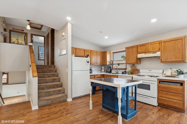 kitchen with light countertops, white appliances, a sink, and under cabinet range hood