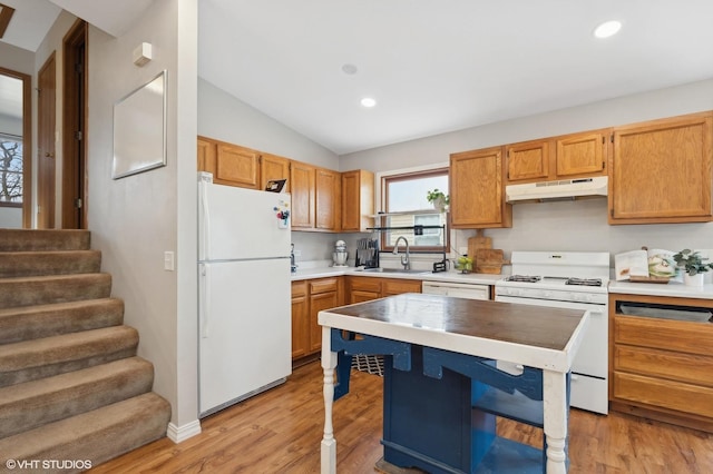 kitchen featuring lofted ceiling, under cabinet range hood, white appliances, a sink, and light wood finished floors