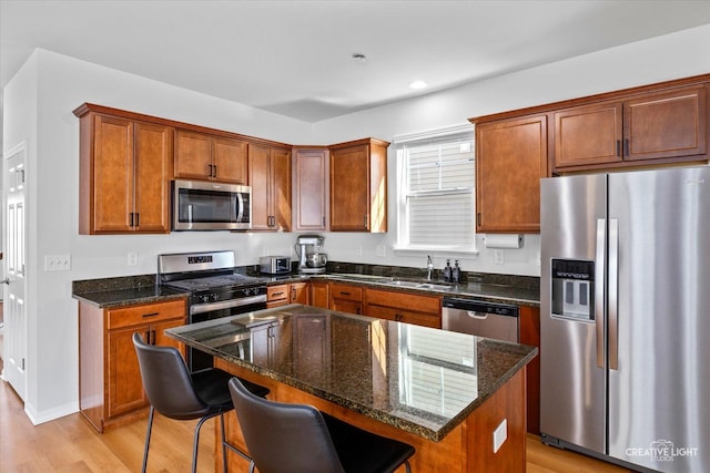 kitchen with light wood-style flooring, appliances with stainless steel finishes, brown cabinetry, and a sink