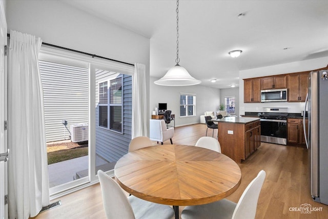 dining area with baseboards, visible vents, and light wood finished floors