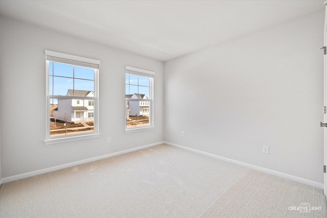 empty room featuring light colored carpet and baseboards