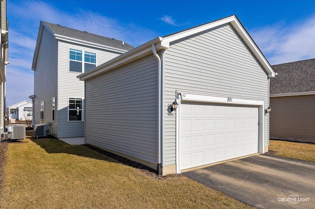 view of side of property with a garage, cooling unit, and a lawn