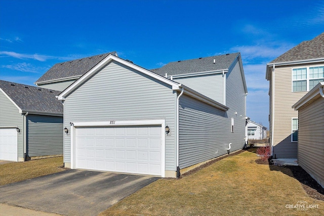 view of side of home with a garage, aphalt driveway, and a lawn