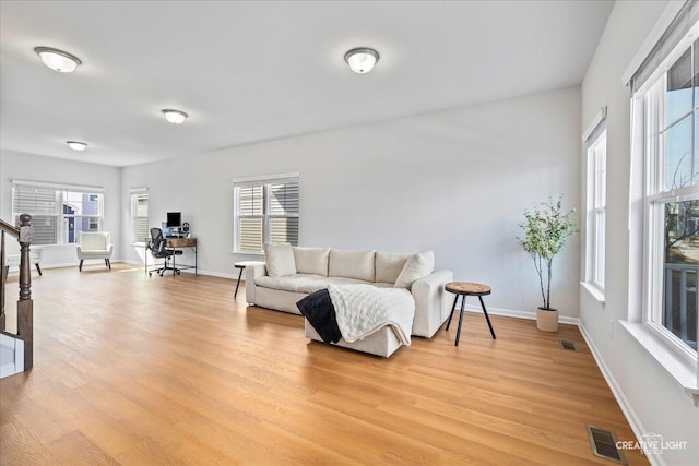 living area featuring stairs, baseboards, visible vents, and light wood-style floors