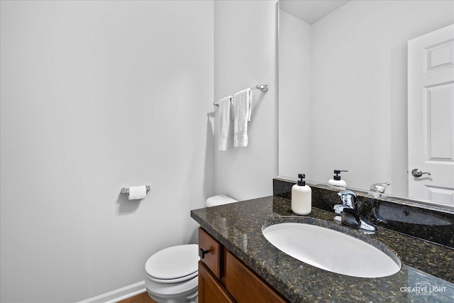 bathroom with baseboards, vanity, and toilet