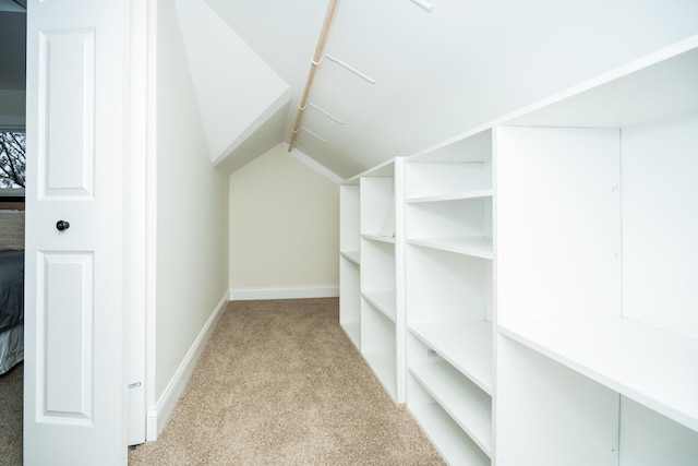 walk in closet featuring light carpet and lofted ceiling