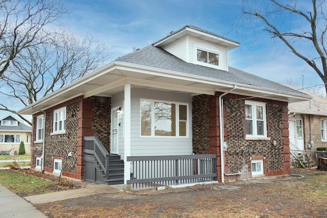 bungalow-style house featuring a shingled roof and brick siding