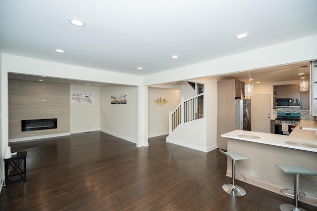 living area with stairway, dark wood-style flooring, a fireplace, and recessed lighting