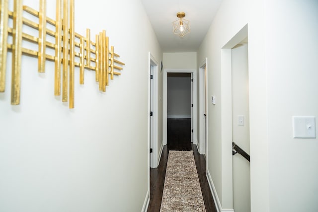 corridor with dark wood-type flooring and baseboards