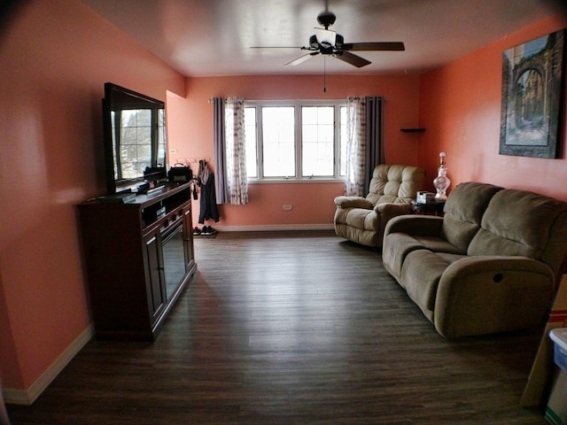 living area with dark wood-style flooring, a ceiling fan, and baseboards