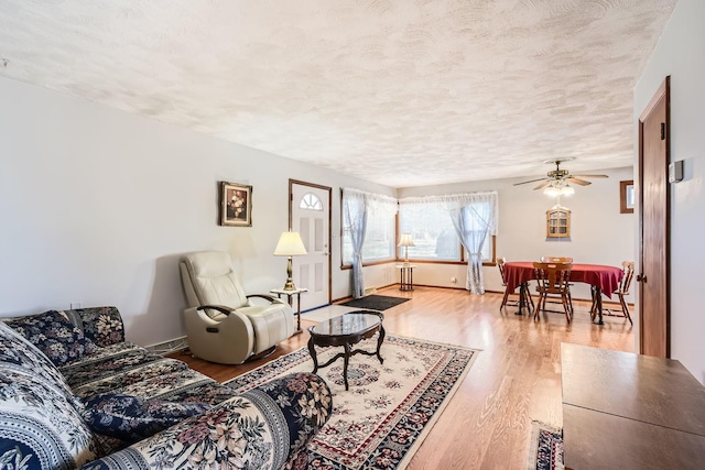 living room featuring a textured ceiling, wood finished floors, a ceiling fan, and baseboards